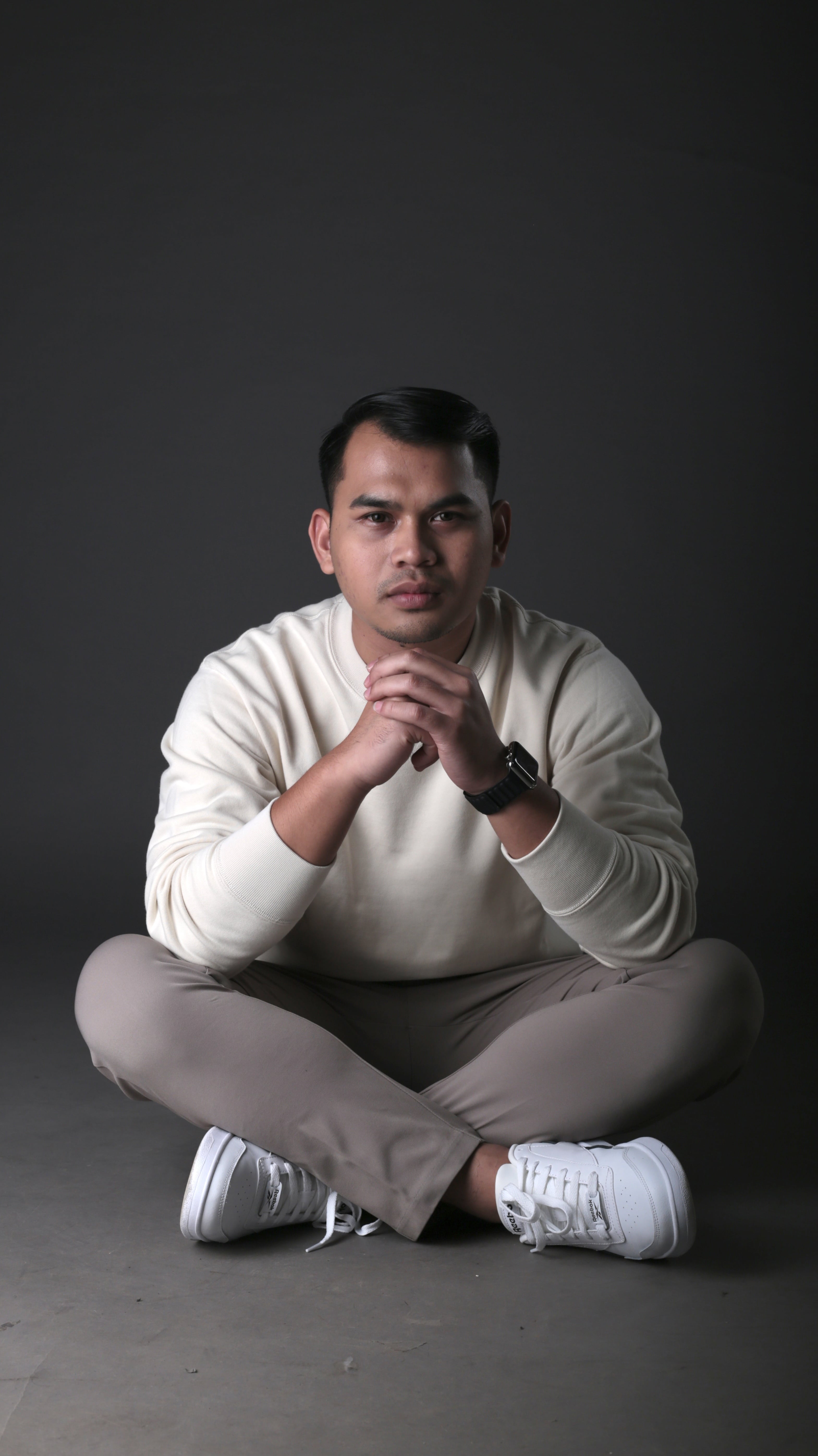 Hida Aldric seated in a relaxed studio portrait