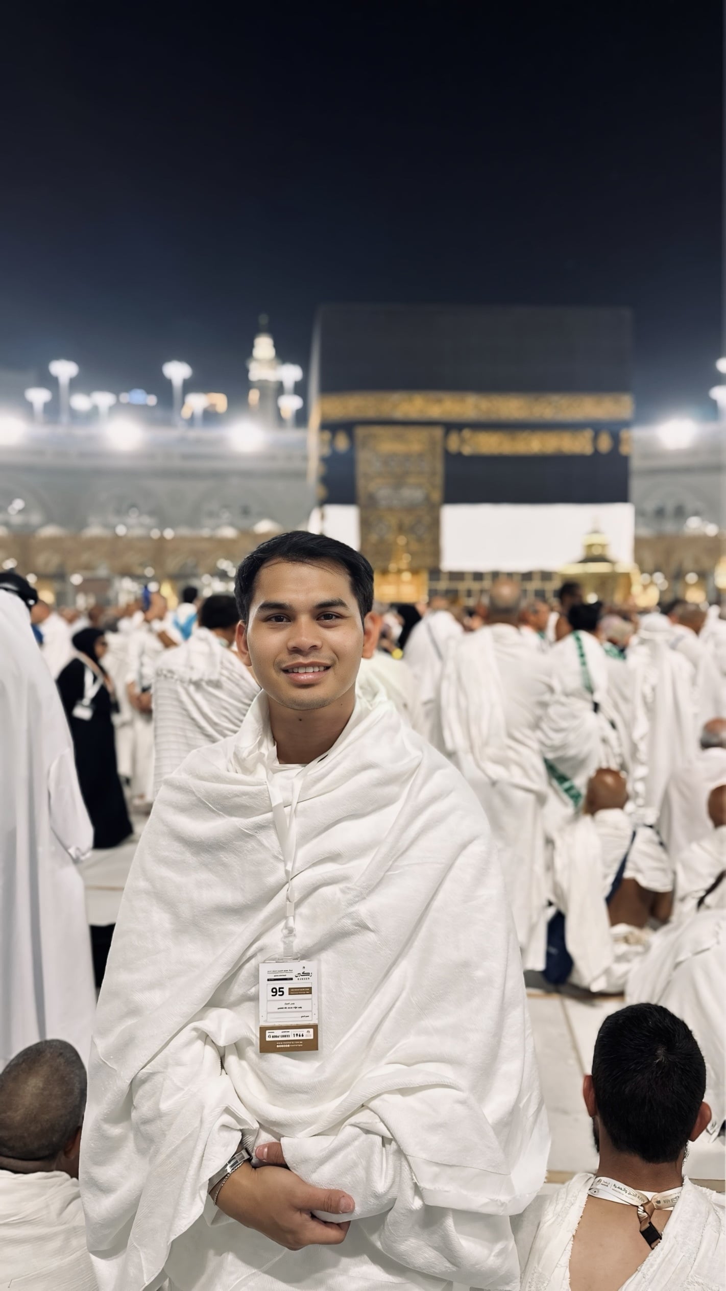 Hida Aldric in pilgrimage clothing with the Kaaba behind him